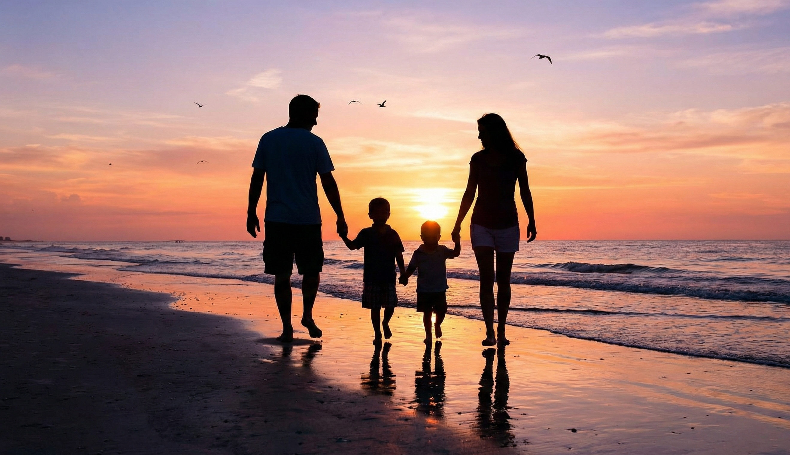 夕暮れの海岸を手をつないで歩く家族のシルエット